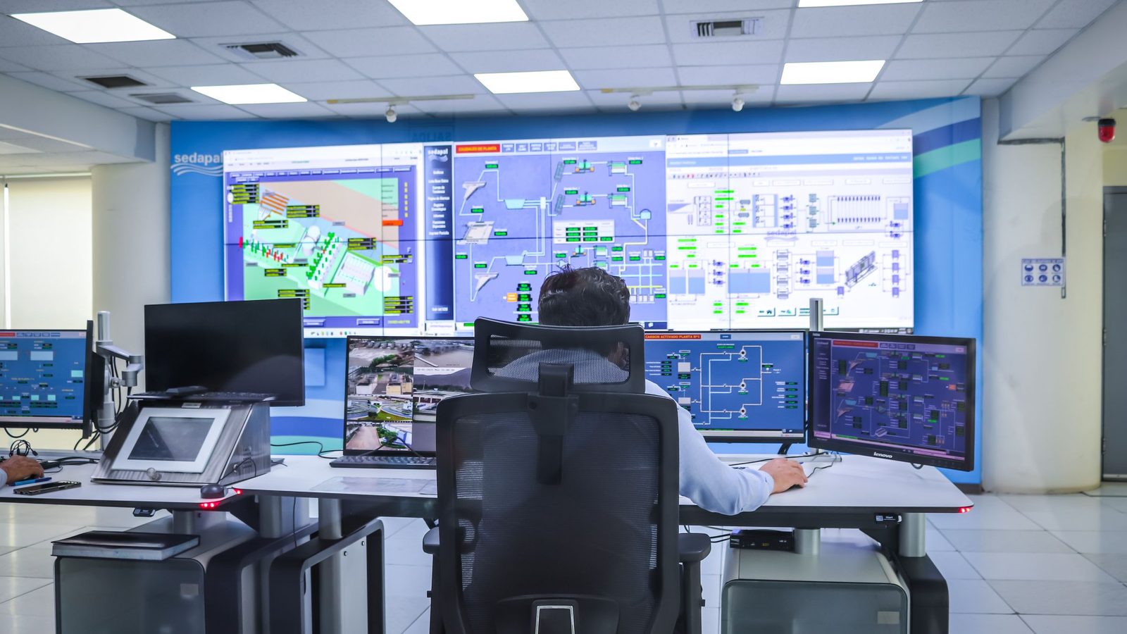 Central de monitoramento com operadores de costas para um painel de telas